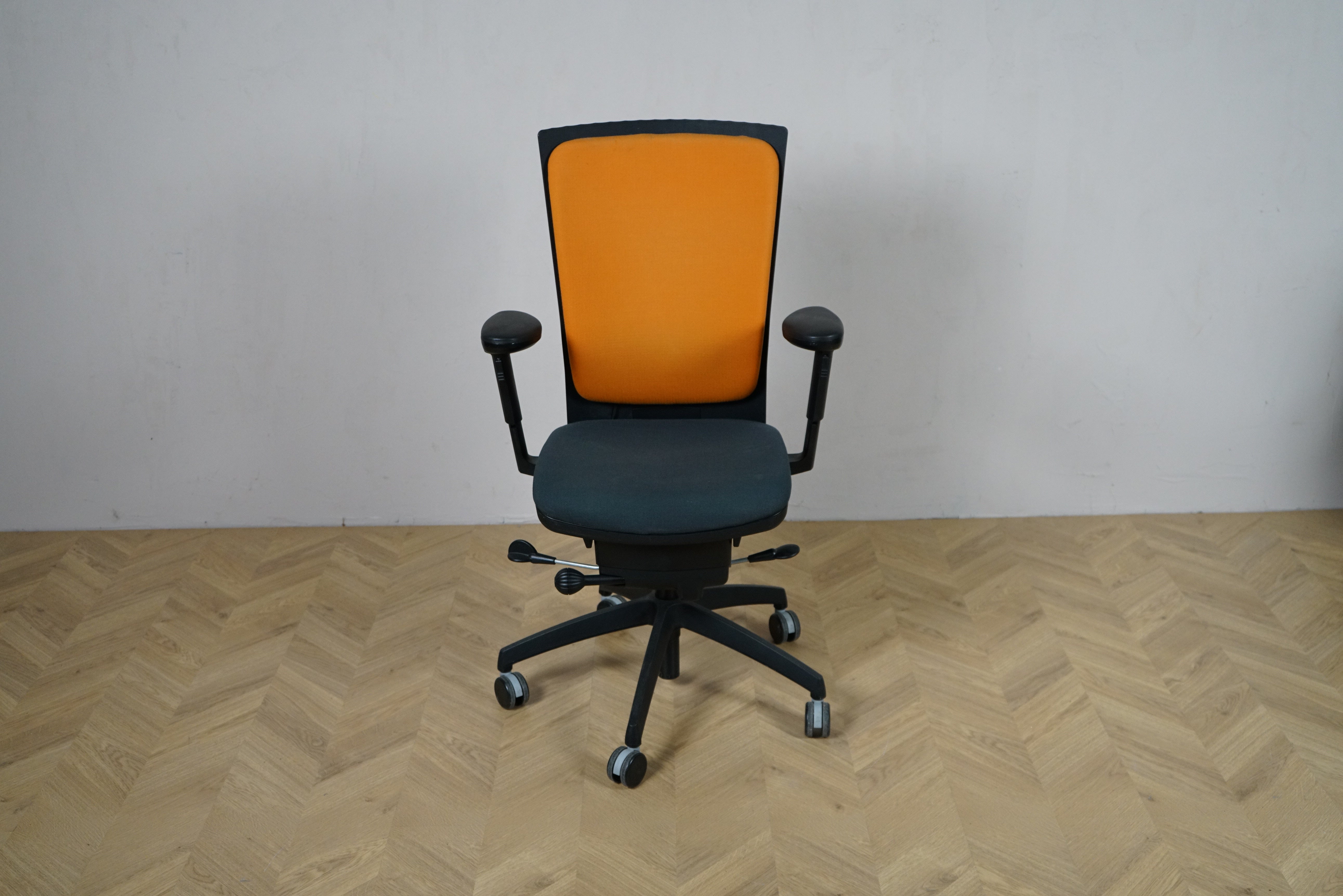 EFG kontorstol set forfra med orange polstret ryglæn, mørkt sæde og armlæn samt sort fodkryds.